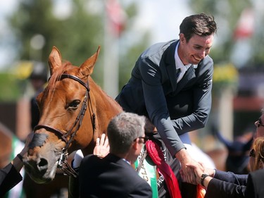 Calgary's Chris Surbey is congratulated in the winners circle after riding Quetchup de la Roque to victory in the Enbridge Classic Derby   during the North American at Spruce Meadows Sunday July 10, 2016.