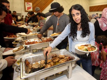 Houda Shivadi fills her plate during the iftar, the breaking of the fast, as Syrian refugees celebrate their first Ramadan in Calgary Tuesday evening June 28, 2016 at Marlborough Community Association.