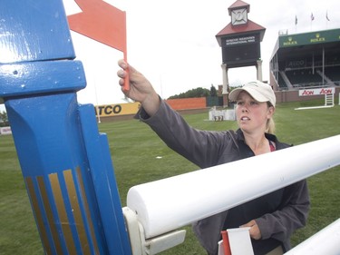 Vivianne Robin of Quebec City, part of the jump crew, sets up a directional flag, red on right, on one of the jumps Tuesday July 5, 2016 prior to the Wednesday start of the Spruce Meadows North American.