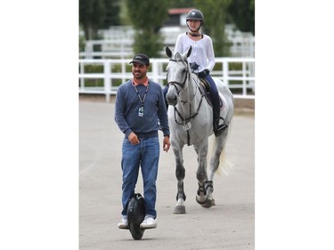 Trainer Nicolas Pizarro Suarez leads his rider Sofia Larrea of Mexico towards the training ring on his one wheel balance scooter Tuesday July 5, 2016 prior to the Wednesday start of the Spruce Meadows North American.