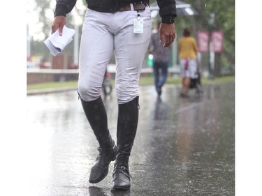 Rider Jack Hardin Towell Jr. and his riding boots walk the laneway as a downpour hits Spruce Meadows during the North American Wednesday  afternoon July 6, 2016.