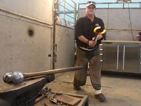 Farrier Heidi Mello pulls a shoe from the oven while working on horseshoeing in a stable area during the  Spruce Meadows North American on July 6, 2016.