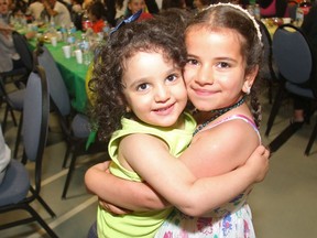 Rashid Mikdad's granddaughters Nahida and Feize Mukdad, hug while playing during the iftar, the breaking of the fast, as Syrian refugees celebrate their first Ramadan in Calgary Tuesday evening June 28, 2016 at Marlborough Community Association.