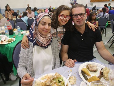 Nour Alraies, her daughter Mira Abbara, age 10, and husband Asiad Abbara, all refugees from Syria, pose while eating during the iftar, the breaking of the fast, as Syrian refugees celebrate their first Ramadan in Calgary Tuesday evening June 28, 2016 at Marlborough Community Association.