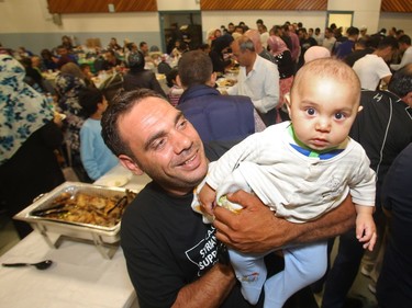 Syrian refugee Atmey Ahmedy holds his son Ahmed during the iftar, the breaking of the fast, as refugees celebrate their first Ramadan in Calgary Tuesday evening June 28, 2016 at Marlborough Community Association.