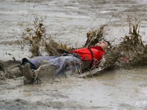 Caleb Bennett from Trementon, Ut., takes a flop in the mud after his bareback ride at the Calgary Stampede rodeo Sunday July 17, 2016. Mike Drew/Postmedia