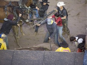 People try to free Gary Gorst's rear pair from the fallen forward pair after they got caught up and turned around on the grandstand stage during heat nine on day nine of Calgary Stampede's GMC Rangeland Derby, on July 16, 2016.