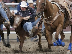 Dakota Eldridge of Elko, Nev., puts in the best steer-wrestling time of Day 5 of the Calgary Stampede Rodeo in Calgary, Alta., on Tuesday, July 12, 2016. Cowboys compete for 10 days for a piece of the rodeo's $2 million in prize money. Lyle Aspinall/Postmedia Network
