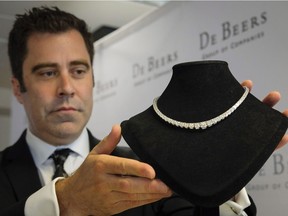 Dylan Dix, of De Beers Canada, holds a diamond necklace at the opening of their facility in Calgary on Wednesday, July 6, 2016.
