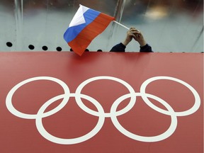FILE - In this Feb. 18, 2014, file photo, a Russian skating fan holds the country's national flag over the Olympic rings before the start of the men's 10,000-meter speedskating race at Adler Arena Skating Center during the 2014 Winter Olympics in Sochi, Russia. On Monday, July 18, 2016 WADA investigator Richard McLaren confirmed claims of state-run doping in Russia.