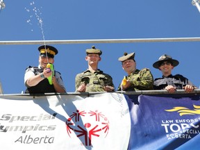 From left; Airdrie RCMP Cpl. Susan Richter, Calgary Highlanders Private Callum Prentice and Cpl. Ross and Alberta bylaw officer Kevin Duval fire water guns and talk to shoppers on Sunday July 24, 2016 while spending 3 days and two nights on a platform at the Airdrie Walmart.