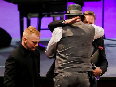 A man hugs Scott and Justin Hamilton after their tribute during a memorial service for Baillie and Baillie's five-year-old daughter Taliyah Marsman at Centre Street Church in Calgary.