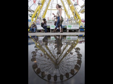 A girl walks by a puddle on the midway during the Calgary Stampede Sneak-a-Peek in Calgary, Alta., on Thursday, July 7, 2016. Stampede would officially kick off the next day and last until July 17. Lyle Aspinall/Postmedia Network
