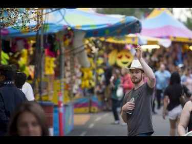 A man waves from the midway during the Calgary Stampede Sneak-a-Peek in Calgary, Alta., on Thursday, July 7, 2016. Stampede would officially kick off the next day and last until July 17. Lyle Aspinall/Postmedia Network