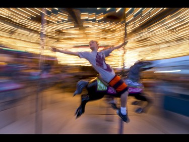 A kid rides a merry-go-round on the midway during the Calgary Stampede Sneak-a-Peek in Calgary, Alta., on Thursday, July 7, 2016. Stampede would officially kick off the next day and last until July 17. Lyle Aspinall/Postmedia Network