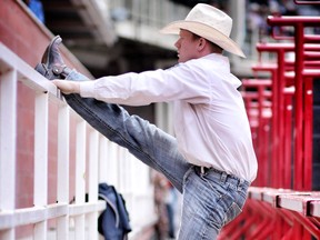 Jacobs Crawley stretches before competing in saddle bronc at the Calgary Stampede in Calgary, Alta., on Tuesday July 12, 2016. Leah Hennel/Postmedia