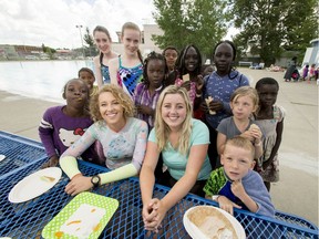 Calgary Swims for Lunch Foundation co-founders Makena Hind (curly hair in front) and Olivia Graham (blonde hair in front) mug for a photo with kids at the Forest Lawn Outdoor Pool.