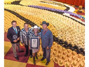 Michael Empric, adjudicator for Guinness World Records; Phil Marleau, general manager of North Hill Shopping Centre; Paula Lee, marketing director for Bentall Kennedy; and Brian Hanson, vide president of Smithbilt Hats Inc., show off the world's largest cowboy hat mosaic, with 2,036 hats included, in Calgary, Alta., on Sunday, July 17, 2016.  The display broke a previous Guinness World Record set in 2011, and the proceeds from the hats sold benefit Cystic Fibrosis Canada. Elizabeth Cameron/Postmedia