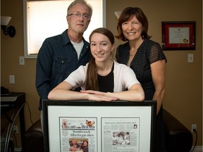 Nicole Boles with dad David and mom Barbara at their home in Calgary, Ab., on Friday July 29, 2016. Nicole is holding a Calgary Herald front page telling the story of her birth on the side of Deerfoot Trail 18 years ago. Mike Drew/Postmedia