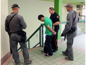 FILE PHOTO: Police have charged Jin Qing Huang, 42, of Calgary with one count of first-degree murder in the death of 51-year-old Tiejun Huang. Jin Qing Huang is escorted in handcuffs form a stabbing incident in the Perpetual Wellness Chinese Medicine Centre on Thursday June 16, 2016 Gavin Young/Postmedia