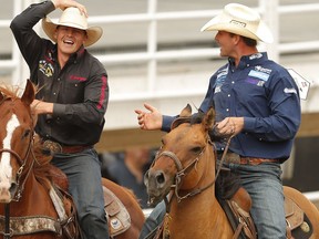 Bulldogger's Cody Cassidy and Casey Martin share the victory lap after the tie-down roping event at the Calgary Stampede rodeo on Wednesday, July 13, 2016. AL CHAREST/POSTMEDIA