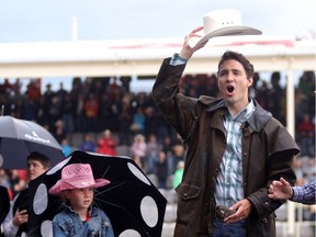 Prime Minister Justin Trudeau with daughter Ella-Grace waves to the crowds during the start of the rodeo at the Calgary Stampede in Calgary, Alta., on Friday July 15, 2016.