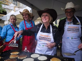 Alberta Premier Rachel Notley, centre, and finance minister Joe Ceci flip pancakes at the annual Premier's Stampede Breakfast in Calgary, on Monday, July 11, 2016.