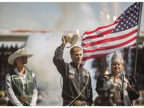 Aryn Toombs/Calgary Herald CALGARY, AB -- July 12, 2015 -- Timber Moore, centre, is escorted to the stage to receive his $100,000 prize for the Tie-Down Roping Championship by Mick Plemel, left, and Lana Waterchief at the Stampede Rodeo at the Stampede Grandstand in Calgary on Sunday, July 12, 2015. (Aryn Toombs/Calgary Herald) (For STAMPEDE story by TBA)  SLUG: 0713 Rodeo