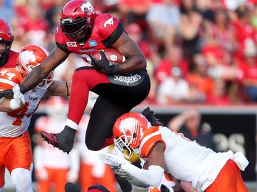 Calgary Stampeders Jerome Messam, left,  tries to evade a tackle from BC Lions Loucheiz Purifoy during CFL action at McMahon Stadium in Calgary, Alta.. on Friday July 29, 2016. Leah hennel/Postmedia