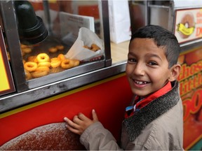 Syrian refugee Abdulla Alzain, 8, waits for mini donuts during his first Calgary Stampede on July 13, 2016. Leah Hennel/Postmedia