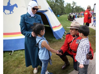 Syrian refugees Ayat Al Sayassneh and her children Hala Daloua ,7, and Ayad Daloua, 5, meet RCMP officer Perry Cardinal at Indian Village during the families first visit to the Calgary Stampede in Calgary, Alta., on Wednesday July 13, 2016. Leah Hennel/Postmedia