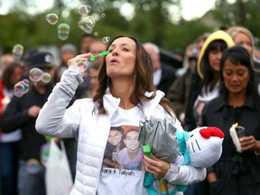 Tanya Kruger blows bubbles during a vigil for Sara Baillie and her daughter, Taliyah Marsman, at Sandstone Park on Sunday.