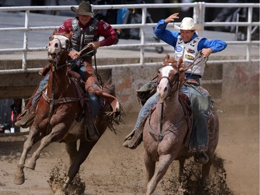 The Demoss brothers Cody, left, and Heith, race during their victory lap after moving on to the saddle bronc final showdown at the Calgary Stampede on Saturday July 16, 2016.