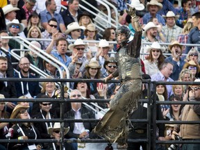 Ty Pozzobon of Merritt, B.C., celebrates after riding Dakota Joe to 83 points in the Ranchman's Renegades Bullbustin' event at the Ranchman's bar in Calgary, on Wednesday, July 6, 2016.