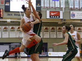 File photo - University of Calgary Dinos Kristie Sheils flies past University of Regina Cougars Alyssia Kajati in basketball action at the UofC Calgary, Ab., on Thursday February 11, 2016.