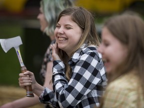 Vaughn Kelly (L) has a laugh with her twin sister Laine while at the Axe Throwing Calgary booth during the Calgary Stampede Sneak-a-Peek in Calgary, Alta., on Thursday, July 7, 2016. Stampede would officially kick off the next day and last until July 17. Lyle Aspinall/Postmedia Network