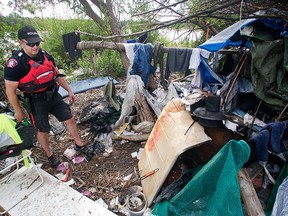 Calgary Police Marine Unit Constable Chris Terner walks through the squalor of an illegal encampment hidden from view in underbrush along the banks of the Bow River near Inglewood Golf Club Monday, August 8, 2016.