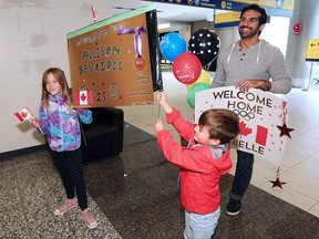 Alice Maitland-Bussoli, 9 and her brother Oscar, 6, as well as Harry Mahesh wait to greet Olympic athletes including cyclist Allison Beveridge and wrestler Danielle Lappage arriving in Calgary on Tuesday, Aug. 23, 2016.