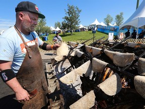 The Guild executive chef Ryan O'Flynn warms bannock next to over half a ton of bison that has been smoked for two days at the Brewery and the Beast event in Calgary on Sunday, Aug. 21, 2016.