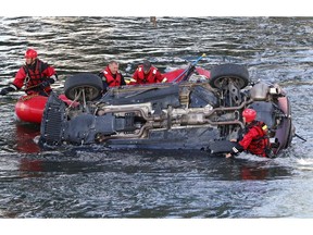 Calgary firefighters work to lift an SUV that left Deerfoot Trail S.E. north of Dunbow Rd and landed in the Bow River on Wednesday August 24, 2016. The driver was taking to hospital in life-threatening condition.  Gavin Young/Postmedia