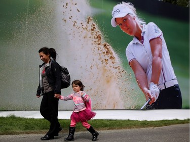 Uyen Weitz and her daughter Sedona, 3, walk by a billboard of Canadian Brooke Henderson at the Canadian Pacific Women's Open at Priddis Greens Golf and Country Club west of Calgary, Alta.,  August 25, 2016.
