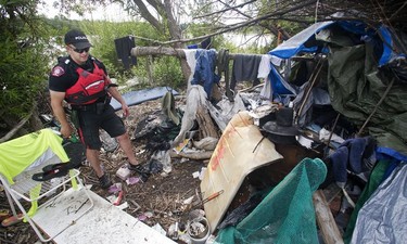 Calgary Police Marine Unit Constable Chris Terner walks through the squalor of an illegal encampment hidden from view in underbrush along the banks of the Bow River near Inglewood Golf Club Monday, Aug. 8, 2016.