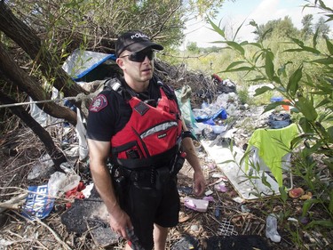 Calgary Police Marine Unit Constable Chris Terner checks out an illegal encampment hidden from view in underbrush along the banks of the Bow River near Inglewood Golf Club Monday, Aug. 8, 2016.