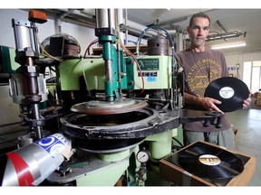 Dean Reid of Canada Boy Vinyl holds up a hot-off-the-press album alongside his record press on Monday.