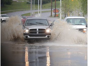 Vehicles crash through a deep section of standing water on 24th Street SE in Quarry Park after another heavy downpour Friday morning July 15, 2016. (Ted Rhodes/Postmedia)
