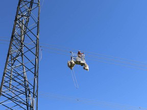 A worker installs reflective bird markers on the transmission line near High River Wednesday,