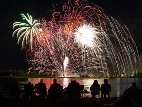 Spectators are silhouetted against the lake as fireworks light up the sky at Globalfest 2016 at Elliston Park in Calgary on August 25, 2016.