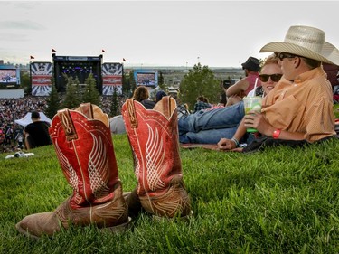 Jayce Fossen kicked off his boots as he and friends Cayley Pelter and Calder Fossen relax on the hill as they listen to Chris Janson performs at day 2 of Country Thunder at Prairie Winds Park in Calgary, Ab., on Saturday August 20, 2016. They came to Country Thunder from Forestburg, Ab. Mike Drew/Postmedia