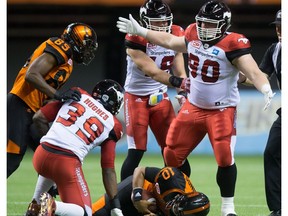 Calgary Stampeders' Quinn Smith, right, celebrates after sacking B.C. Lions' quarterback Jonathon Jennings, bottom, during the second half of a CFL football game in Vancouver, B.C., on Friday August 19, 2016.