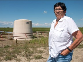 Lana Bulger with a gas well in the middle of a field of barley on her farm northwest of Nanton.